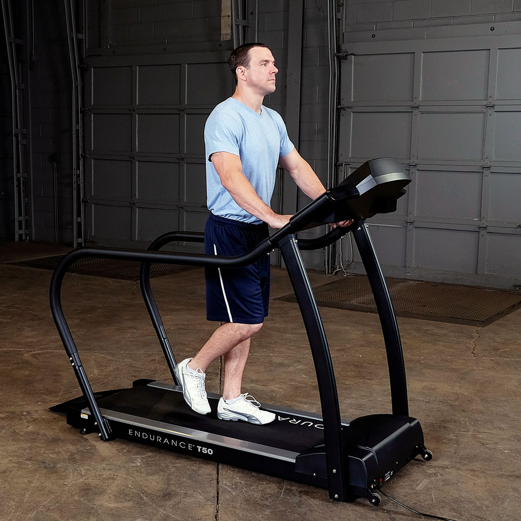 User walking on the Endurance T50 walking treadmill holding the full-length thick handrails