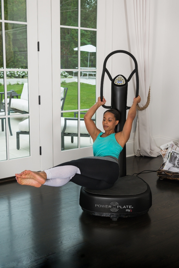 Woman performing a seated core hold while gripping the handles of a Power Plate my5