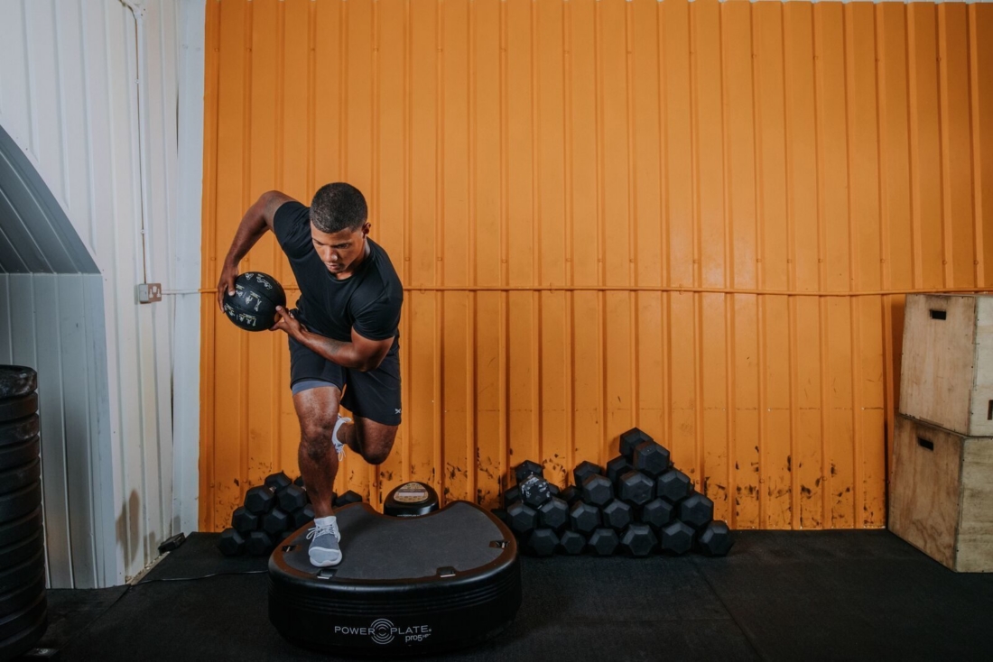 Athlete training with medicine ball on Power Plate pro5HP vibration platform