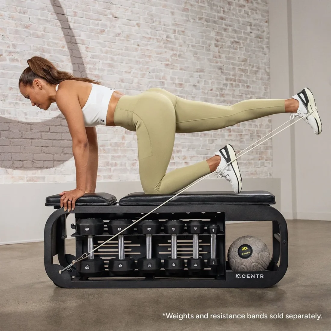 Woman using the front band anchors on the Centr Fusion Bench for a banded kickback