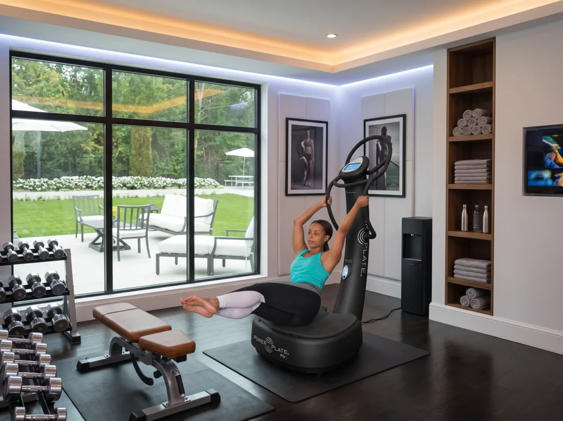 Woman doing a seated core exercise on the upgraded Power Plate my5 in a home gym